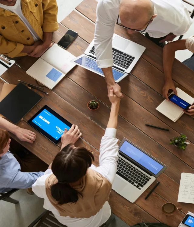 Equipo alrededor de una mesa repartiendo el trabajo con notebooks y tablets